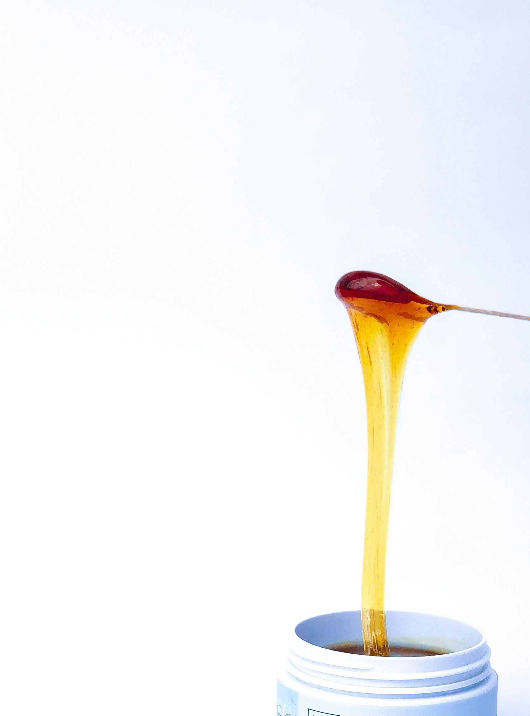 a jar of sugar wax with a spoon sticking out of it